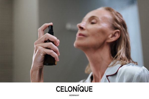 Mature woman applying a facial skincare mist during her home routine, with CELONIQUE Germany branding.
